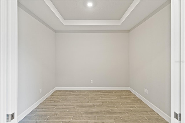 unfurnished room with a raised ceiling and light hardwood / wood-style flooring