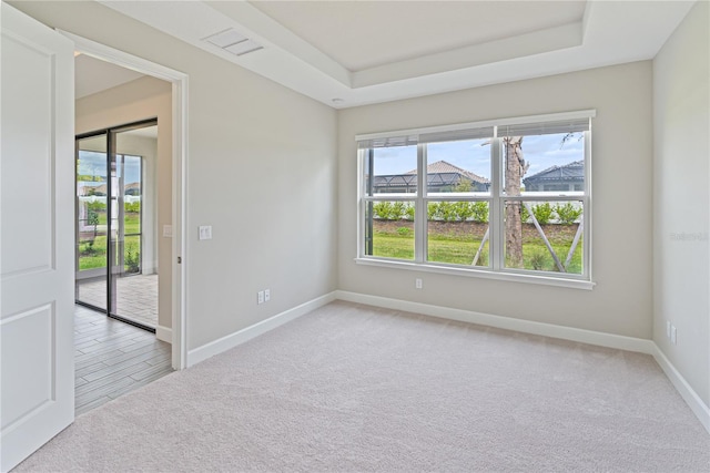 carpeted empty room featuring a tray ceiling