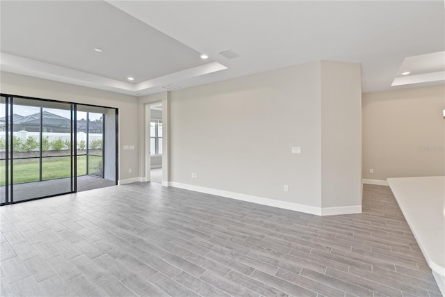 spare room with a raised ceiling, light hardwood / wood-style floors, and a mountain view