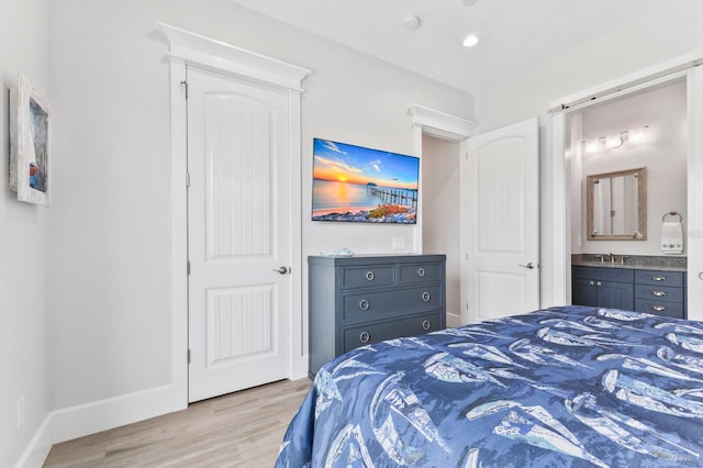 bedroom with light hardwood / wood-style flooring and connected bathroom