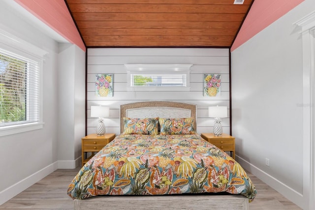 bedroom featuring wooden walls, vaulted ceiling, light hardwood / wood-style floors, and wooden ceiling