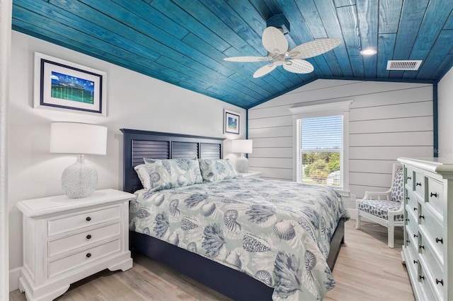 bedroom with light hardwood / wood-style floors, wood ceiling, lofted ceiling, ceiling fan, and wooden walls