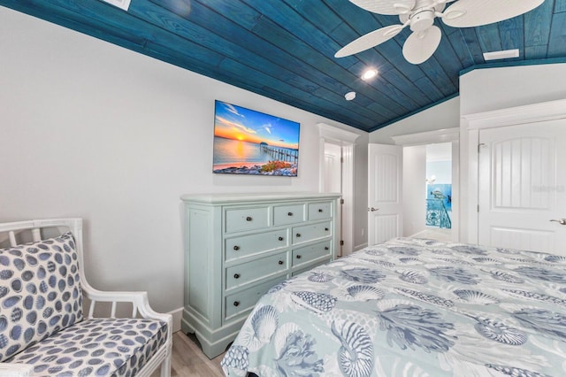 bedroom with light hardwood / wood-style floors, vaulted ceiling, ceiling fan, and wooden ceiling