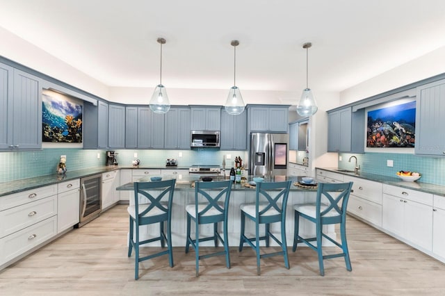 kitchen featuring pendant lighting, stainless steel appliances, wine cooler, and light hardwood / wood-style floors