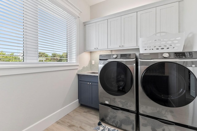 laundry room with washer and clothes dryer, cabinets, and light wood-type flooring