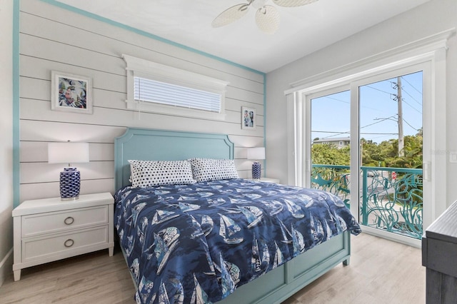 bedroom with light hardwood / wood-style floors, wood walls, ceiling fan, and access to exterior