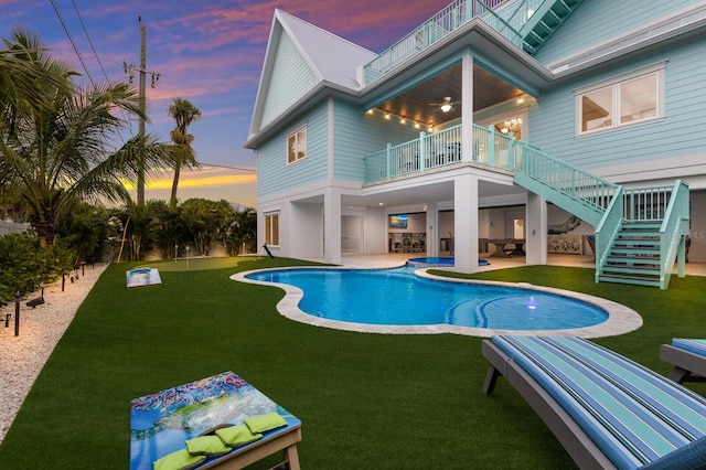 pool at dusk featuring a lawn and a patio