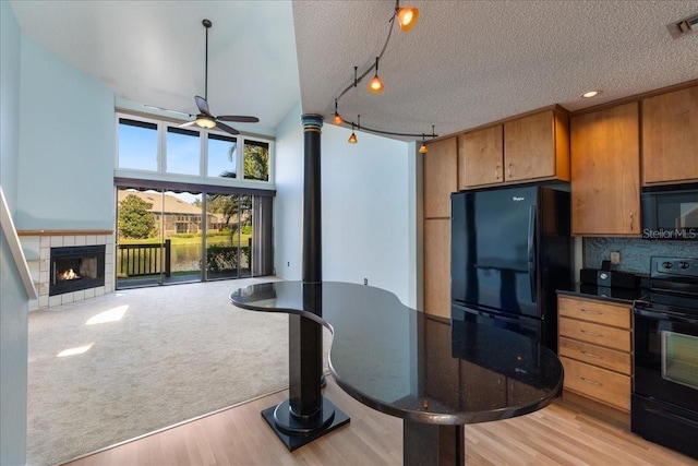 kitchen featuring tasteful backsplash, ceiling fan, a textured ceiling, light wood-type flooring, and black appliances