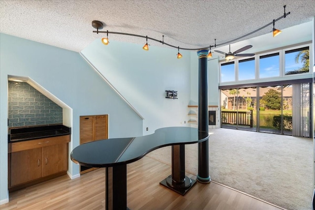 misc room featuring rail lighting, ceiling fan, a textured ceiling, and light hardwood / wood-style flooring