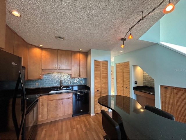 kitchen featuring light hardwood / wood-style flooring, black appliances, sink, and backsplash