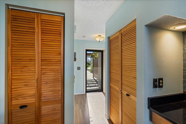 hallway with a textured ceiling and light wood-type flooring