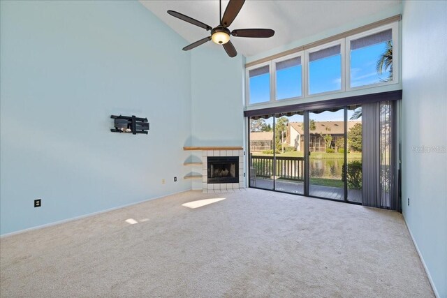 unfurnished living room with a tile fireplace, light colored carpet, high vaulted ceiling, and ceiling fan