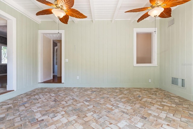 unfurnished room with beamed ceiling and wooden walls