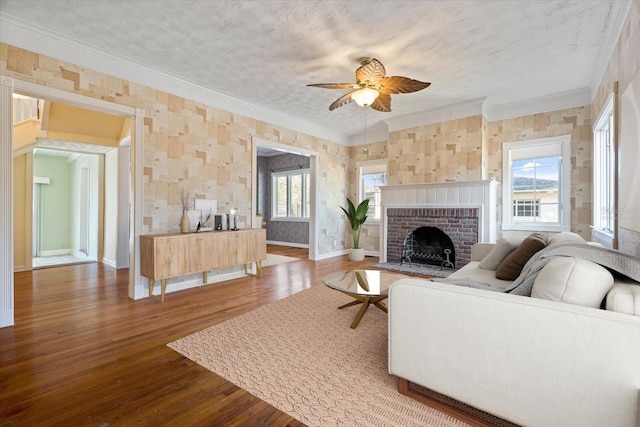 living room with hardwood / wood-style floors, plenty of natural light, a fireplace, and crown molding