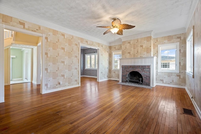 unfurnished living room with ceiling fan, wood-type flooring, a textured ceiling, a fireplace, and ornamental molding