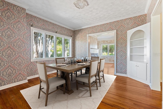 dining room with hardwood / wood-style floors, built in shelves, and crown molding