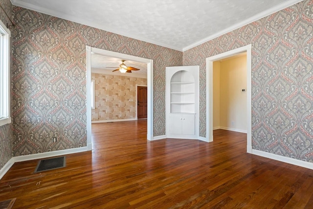 empty room with ceiling fan, built in features, a textured ceiling, hardwood / wood-style flooring, and ornamental molding