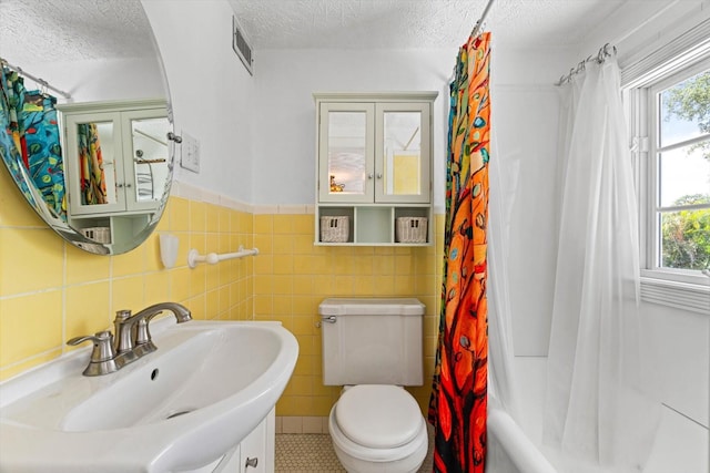 full bathroom featuring a textured ceiling, shower / bath combo with shower curtain, tile walls, tile patterned flooring, and toilet