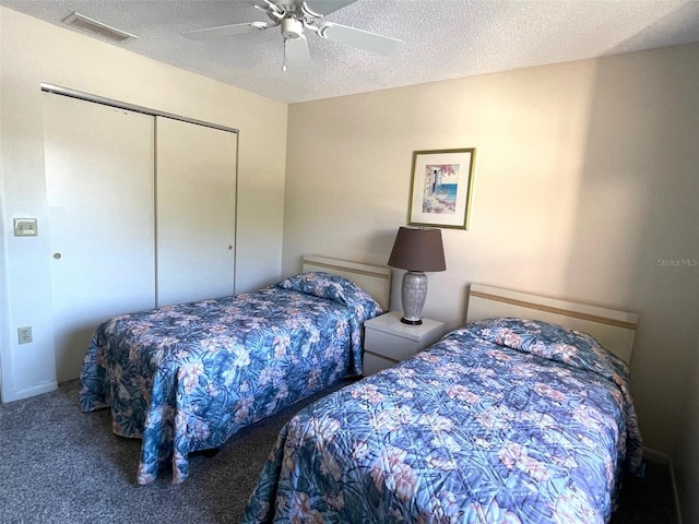 bedroom featuring a closet, ceiling fan, dark carpet, and a textured ceiling