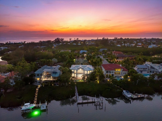 aerial view at dusk featuring a residential view and a water view