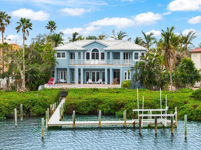 back of property with a water view, a balcony, metal roof, and french doors