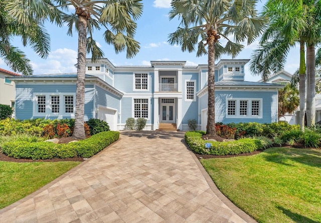 neoclassical home featuring driveway, a standing seam roof, french doors, a front yard, and metal roof