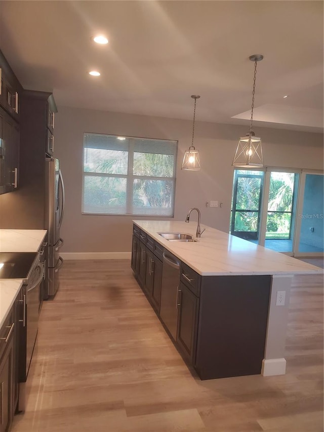 kitchen featuring appliances with stainless steel finishes, sink, light hardwood / wood-style flooring, dark brown cabinets, and pendant lighting