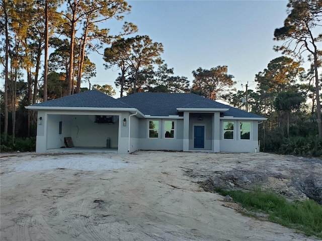 view of front of home with stucco siding, an attached garage, and driveway