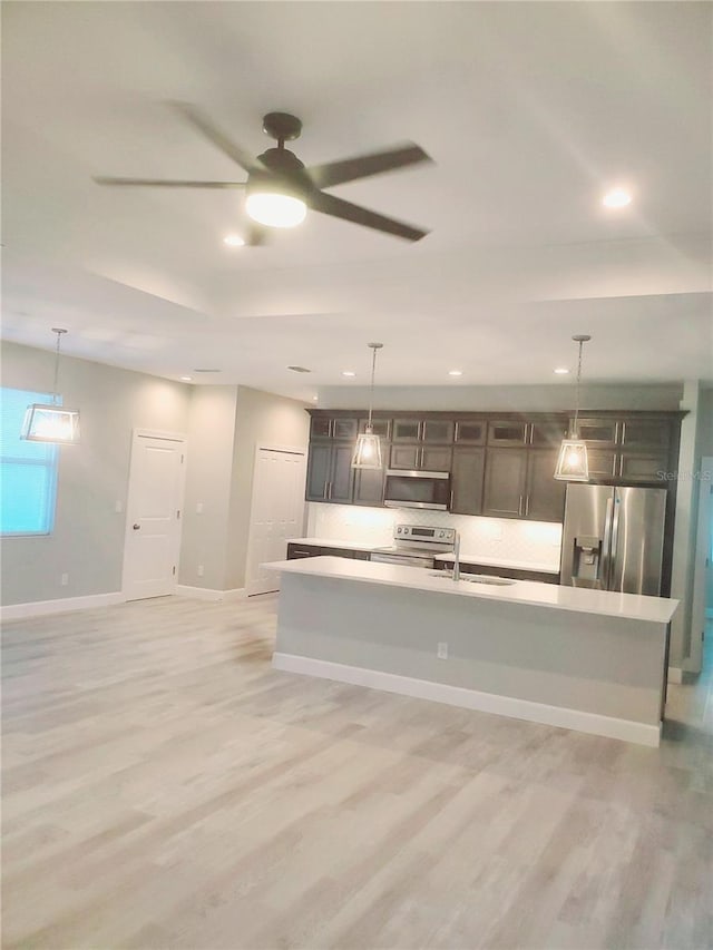 kitchen featuring stainless steel appliances, light wood finished floors, baseboards, and light countertops