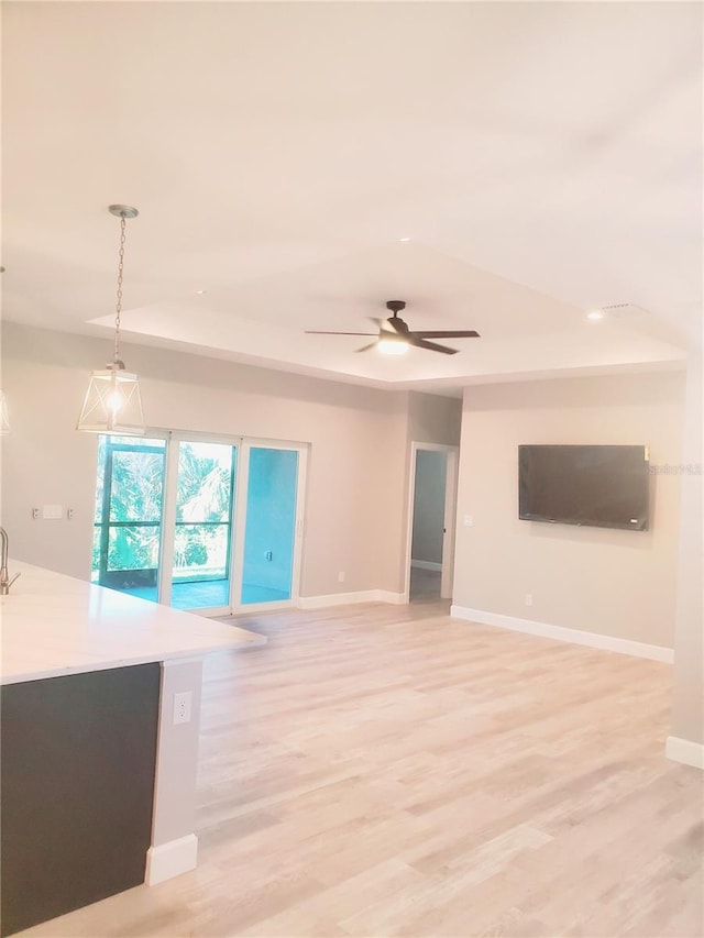 unfurnished living room featuring ceiling fan, baseboards, and light wood-style flooring