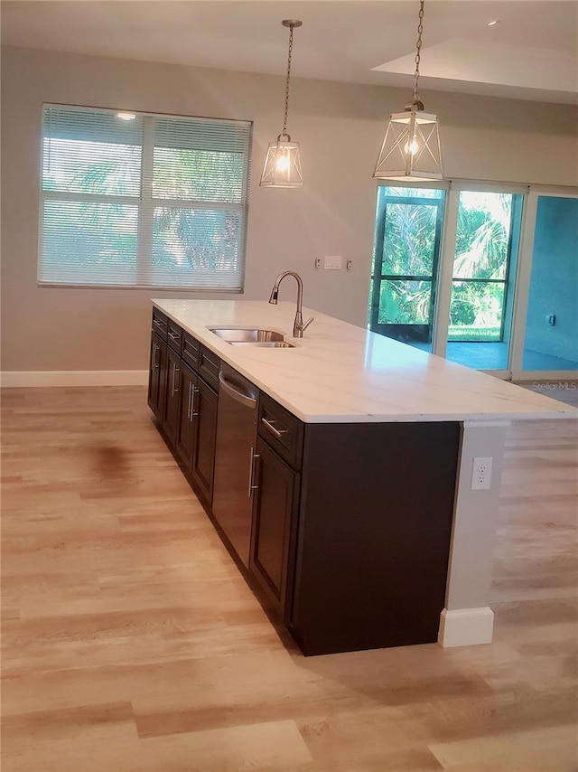 kitchen with a sink, dark brown cabinets, light wood-style floors, pendant lighting, and dishwasher