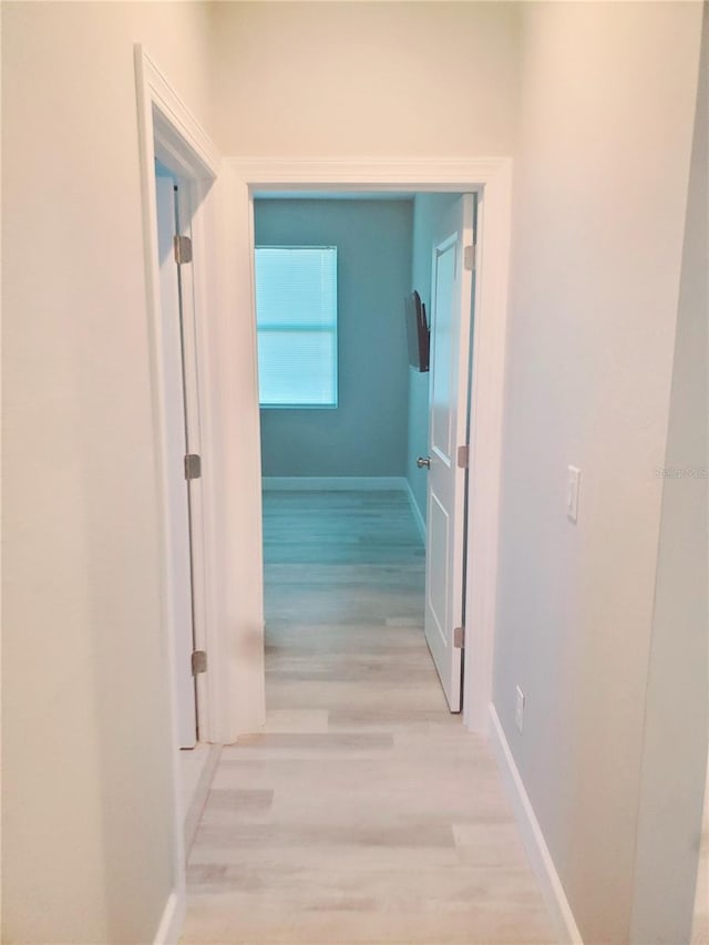 hallway with light wood-style flooring and baseboards