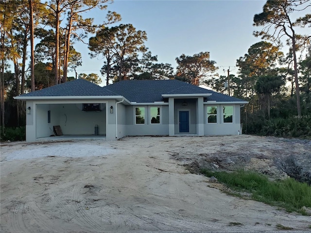 view of front of property featuring a shingled roof, a garage, driveway, and stucco siding