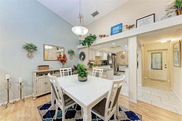 dining area with lofted ceiling, sink, and light tile flooring