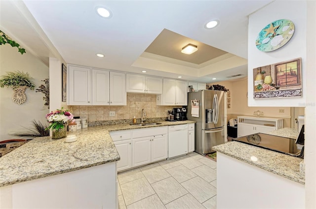 kitchen with stainless steel fridge, tasteful backsplash, white cabinets, a tray ceiling, and sink