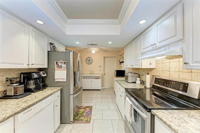 kitchen featuring a tray ceiling, ceiling fan, stainless steel appliances, white cabinets, and crown molding