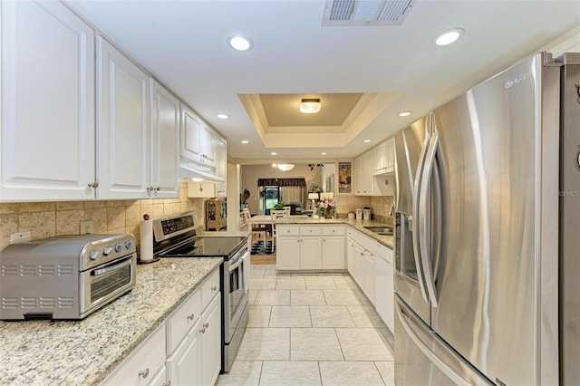 kitchen with appliances with stainless steel finishes, white cabinetry, backsplash, and light tile flooring