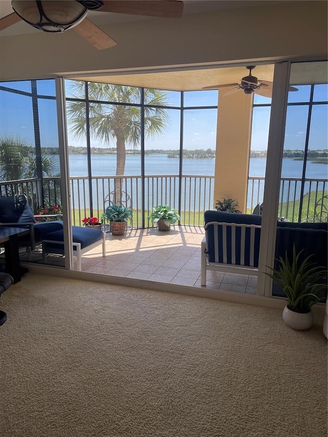 sunroom with ceiling fan and a water view