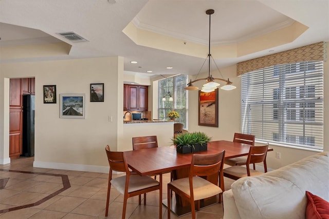 dining area with an inviting chandelier, light tile patterned floors, crown molding, and a tray ceiling