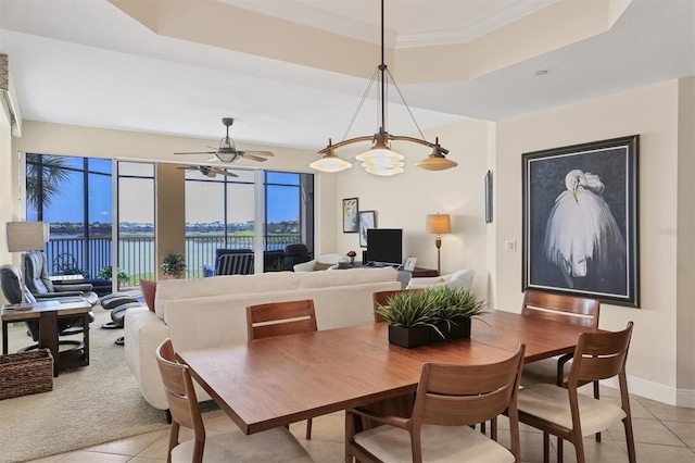 tiled dining area featuring ceiling fan with notable chandelier and a tray ceiling