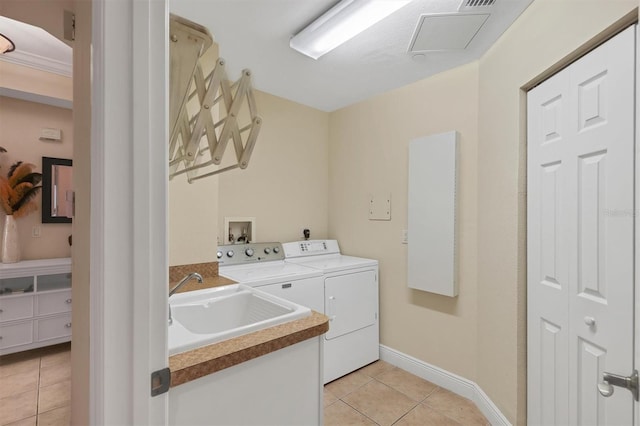 laundry area with light tile patterned floors, sink, and washing machine and clothes dryer