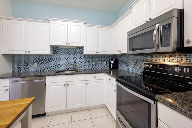 kitchen with light tile patterned floors, sink, appliances with stainless steel finishes, white cabinetry, and backsplash