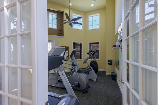 exercise area with ceiling fan, a healthy amount of sunlight, and a high ceiling