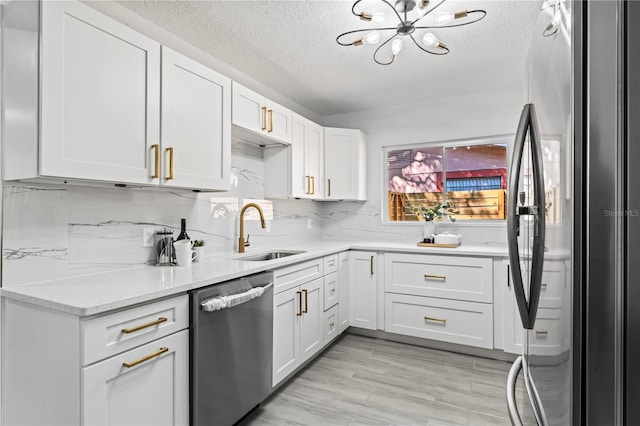 kitchen with a textured ceiling, sink, stainless steel appliances, and a notable chandelier