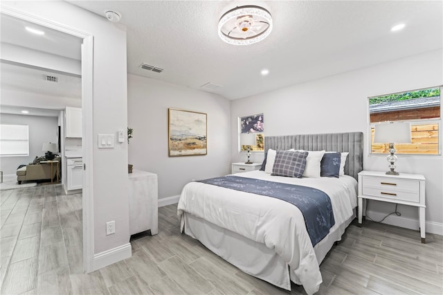 bedroom with light hardwood / wood-style floors and a textured ceiling