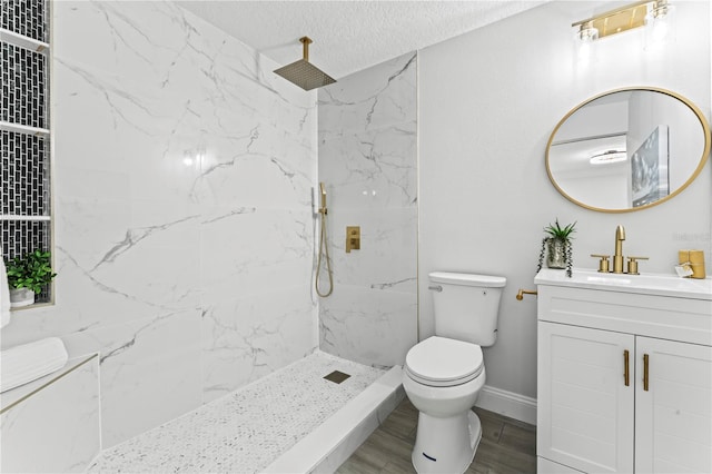 bathroom with toilet, hardwood / wood-style floors, vanity, a textured ceiling, and tiled shower