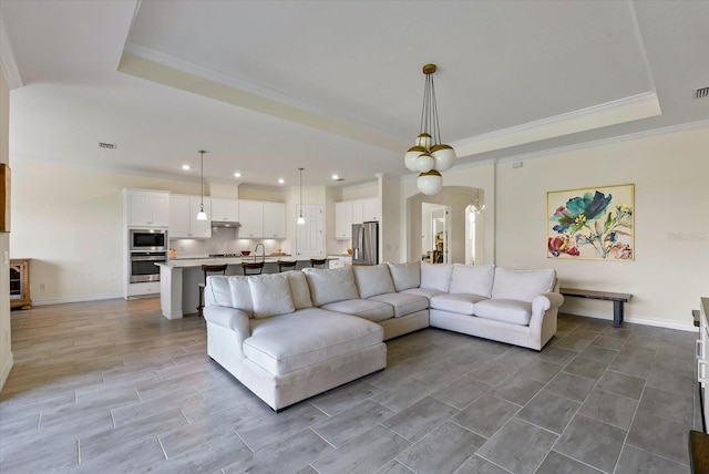 living room with a notable chandelier, crown molding, and a tray ceiling