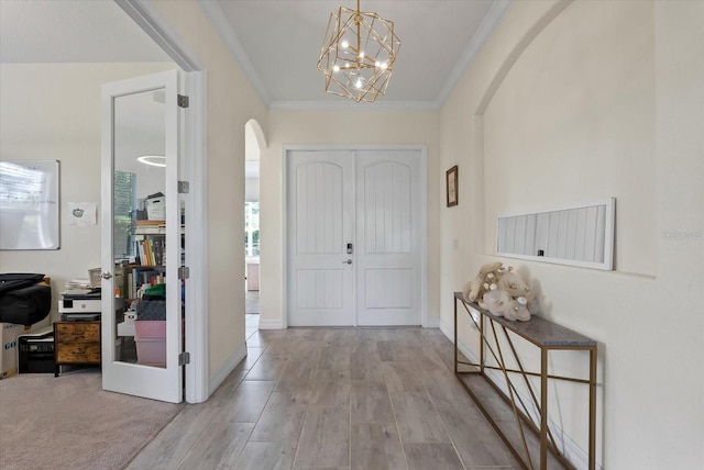 entryway with a chandelier, light hardwood / wood-style flooring, and ornamental molding