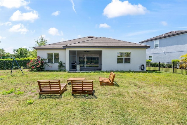 rear view of property with a lawn, a sunroom, and a playground