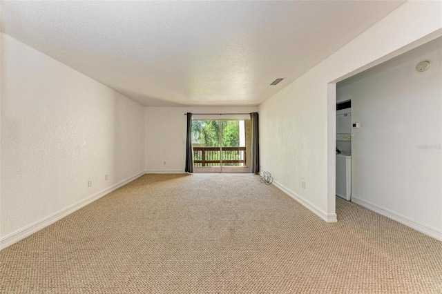 carpeted empty room featuring stacked washer and clothes dryer